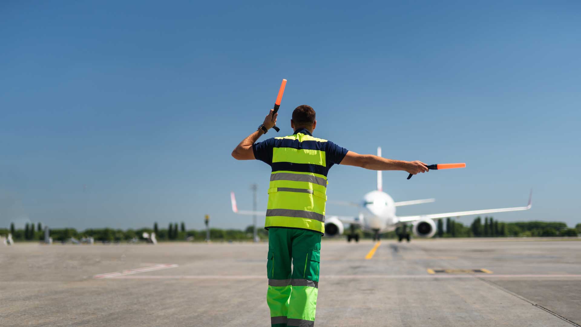 Airport ground crew member guiding an airplane on the tarmac, representing La Casa Jet’s compliance and legal operations services for aircraft.