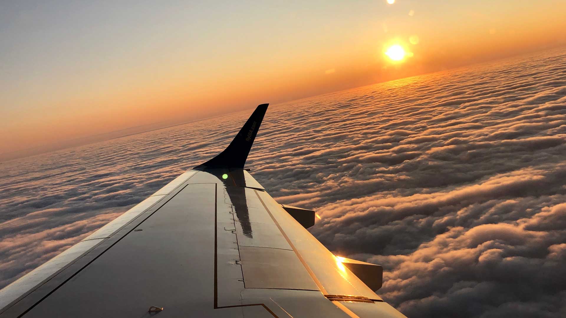 Private jet wing above the clouds at sunset, capturing the elegance of flight.
