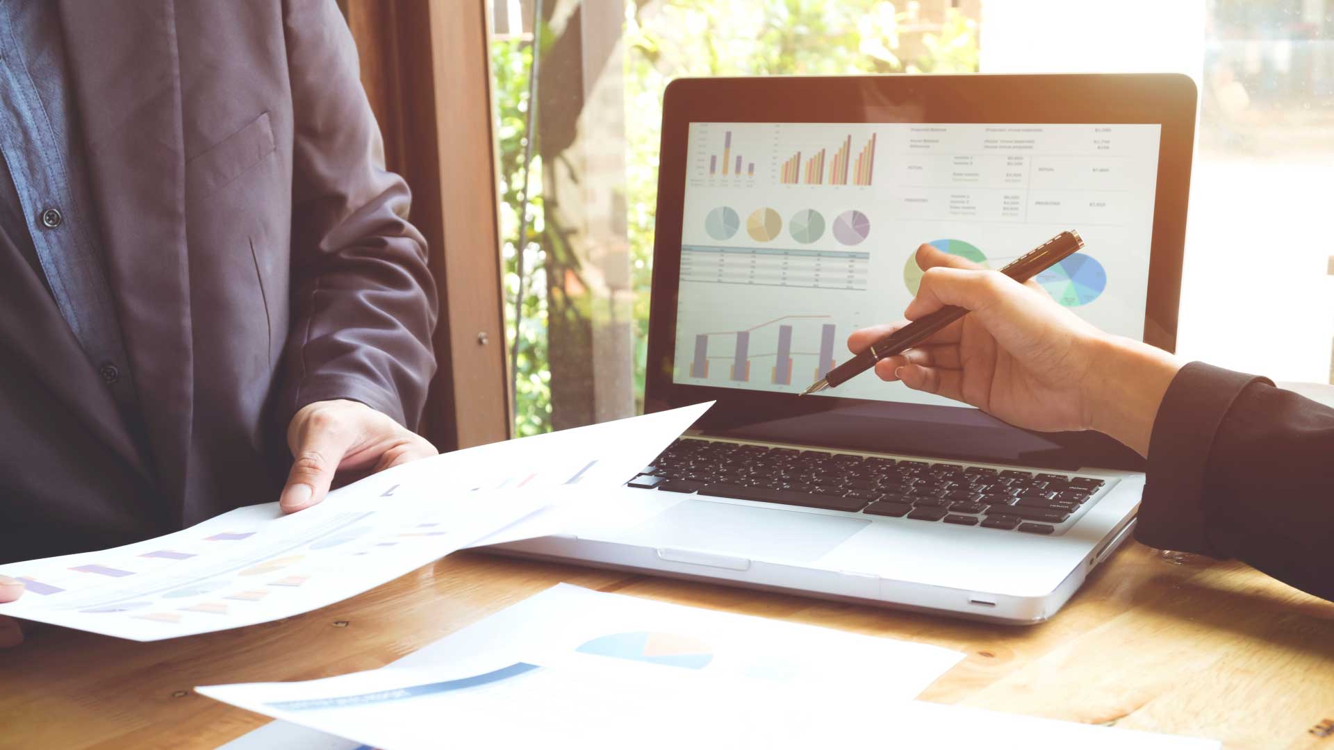 Business professionals reviewing aircraft financial data and fuel optimization reports on a laptop for private jet management.