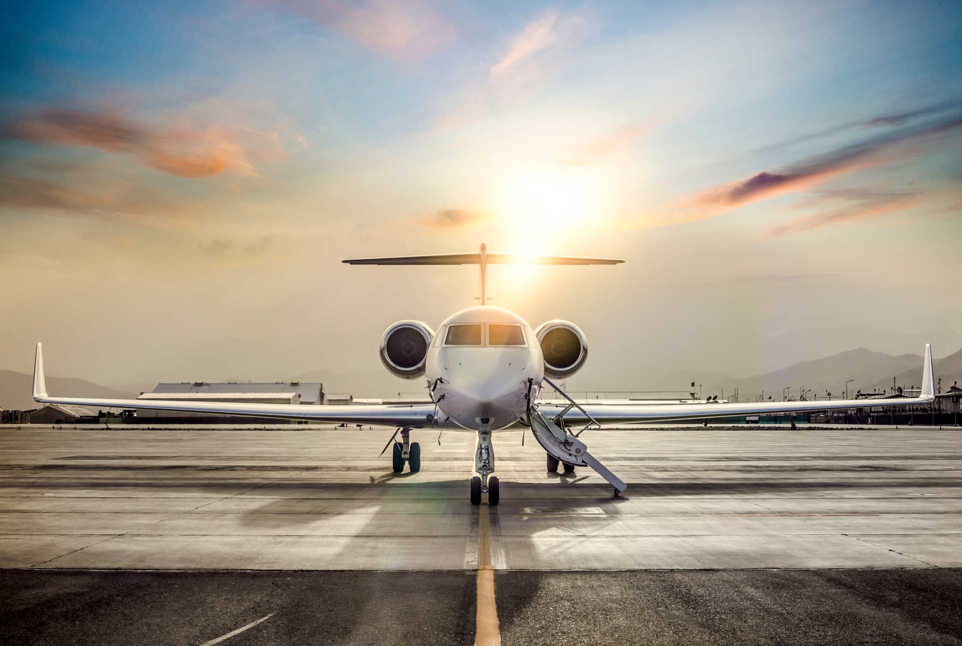 Private jet parked on runway at sunrise with mountains in the background, representing La Casa Jet's boutique, transparent, and technology-driven approach to jet management.